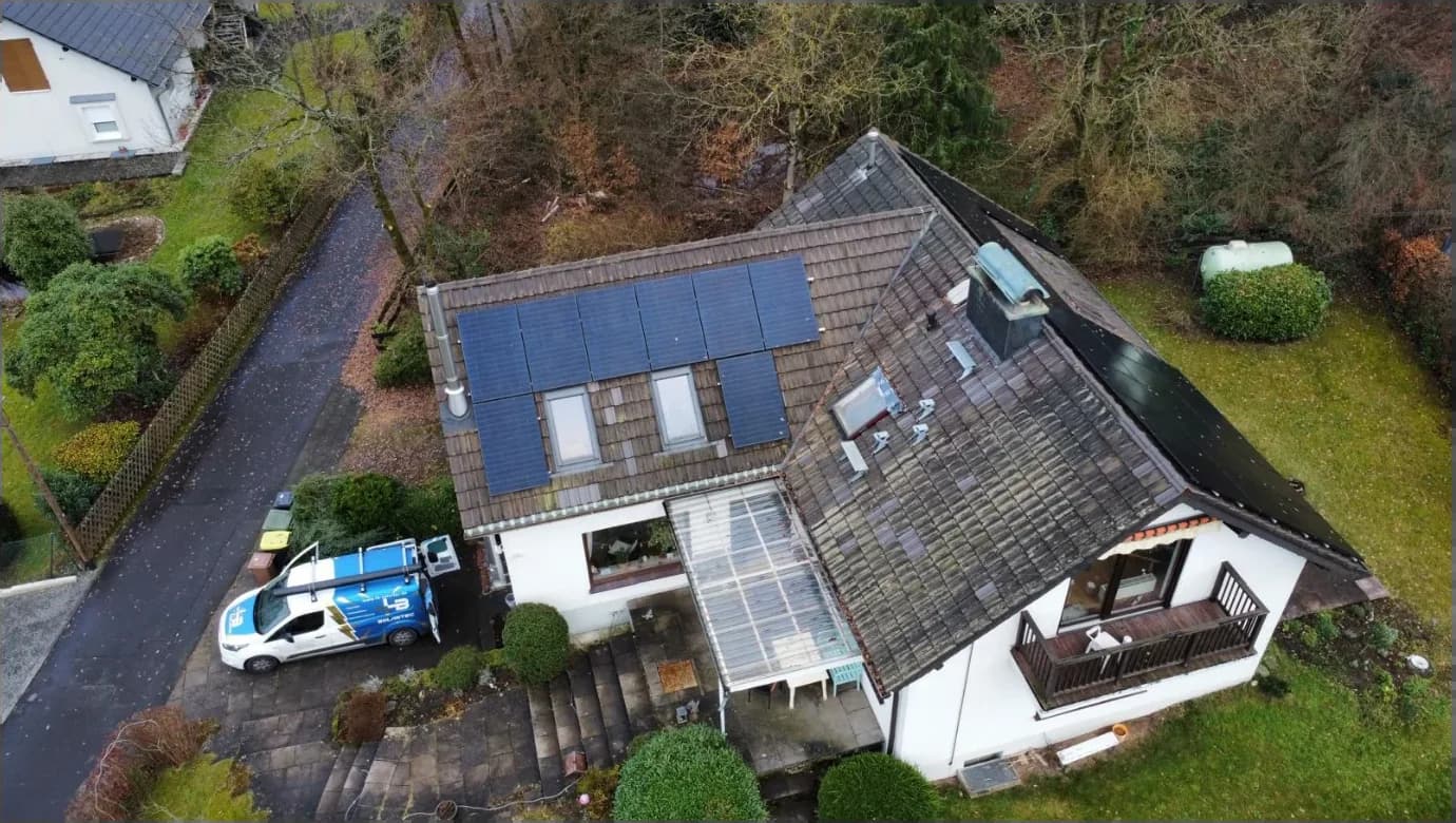 Drohnenaufnahme einer von LB-Solartec installierten Photovoltaik-Anlage auf einem Einfamilienhaus in der Region Bonn, mit LB-Solartec-Servicefahrzeug